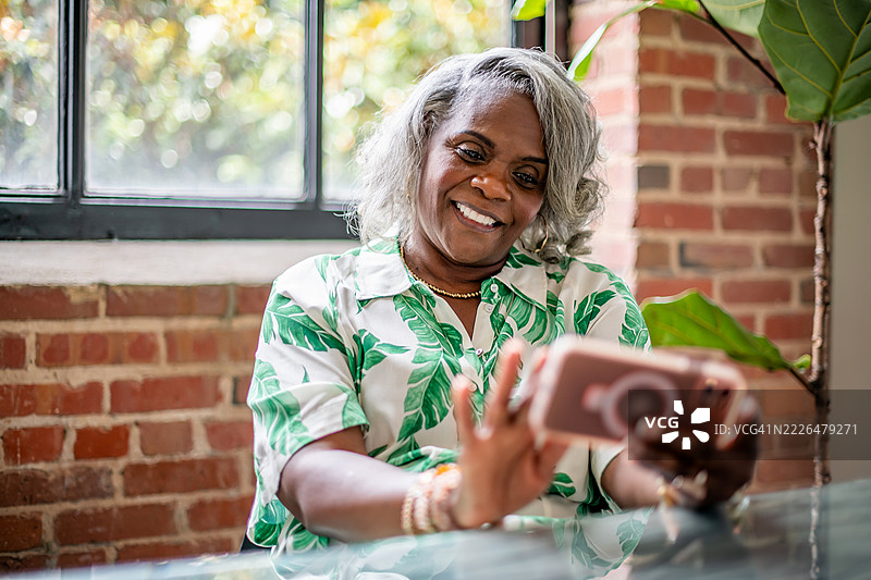 成熟的女性在休息期间使用移动设备图片素材