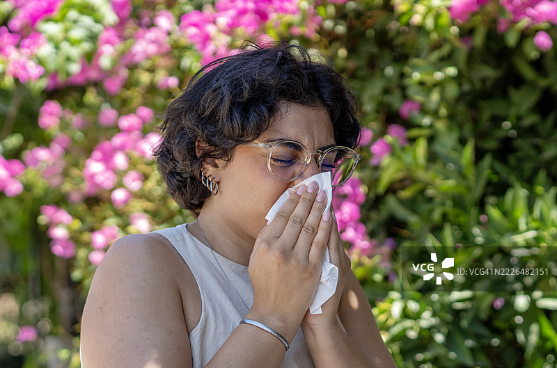 因季节性过敏而在户外打喷嚏的女性图片素材