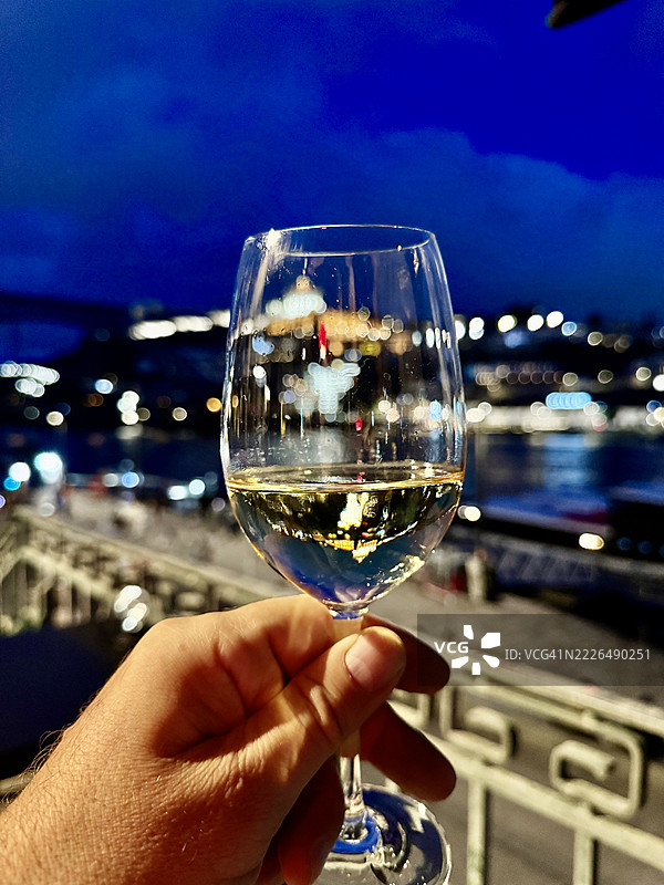 夜晚的白葡萄酒与波尔图的城市灯光相映成趣。图片素材
