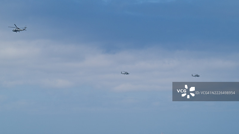 三架MH-60R海鹰直升机在多云的天空中编队飞行图片素材