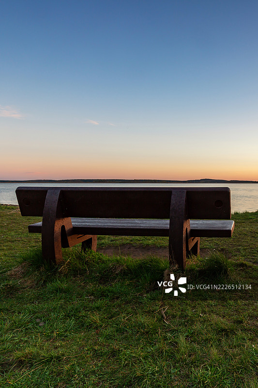 日落时分，湖边草地上的长椅图片素材