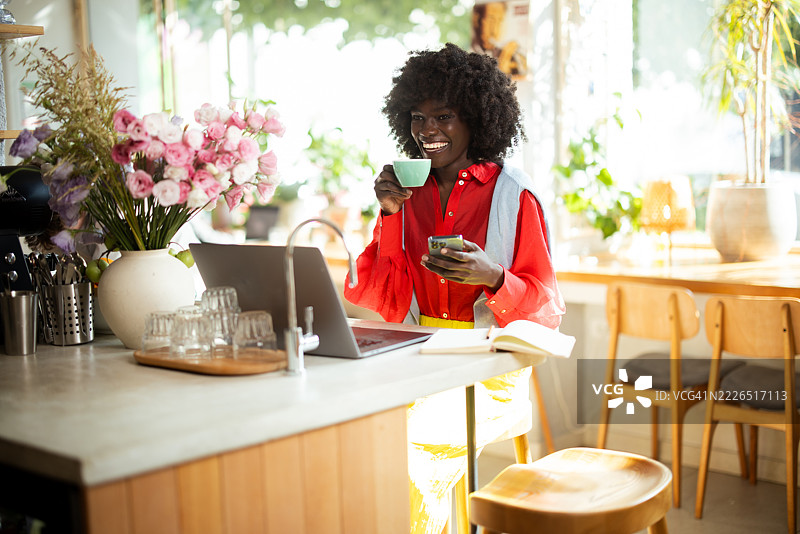 花店里的花店老板喝着咖啡，使用智能手机。图片素材