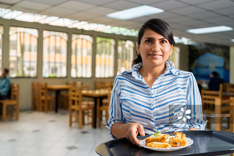 拉丁美洲女服务员在海鲜餐厅端着一盘炸鱼图片素材
