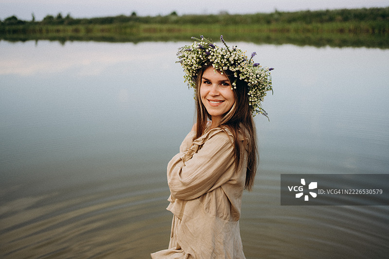 年轻女性戴着花冠，享受湖边的自然风光图片素材
