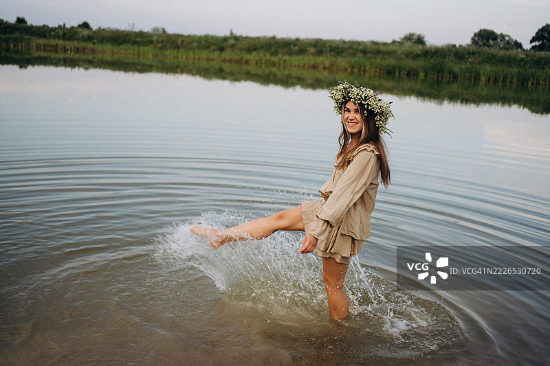 年轻女性在夏至庆祝活动中，头戴花环在湖中嬉水图片素材