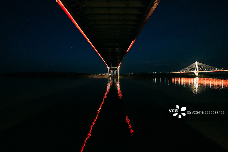 黄昏时分，河上桥下的红色灯光倒影图片素材