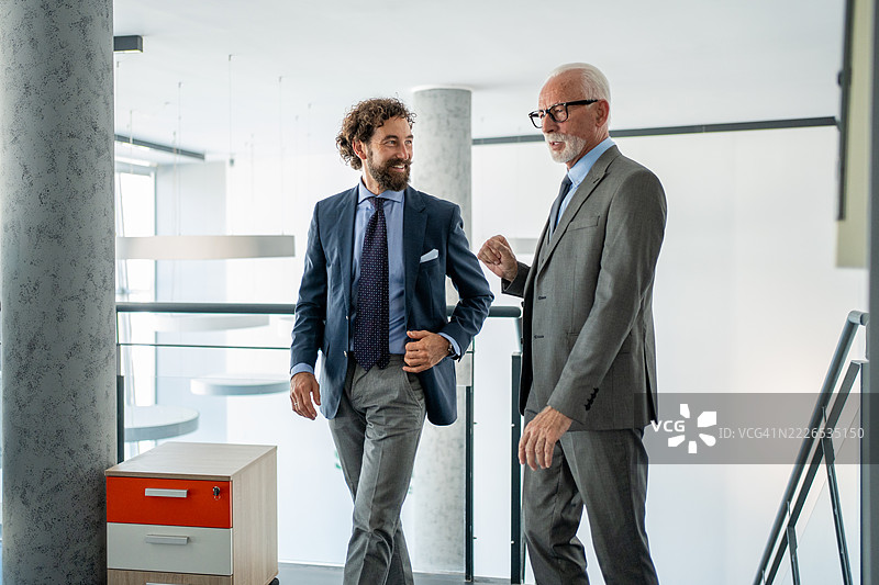 两位商人在现代办公室里边走边谈图片素材