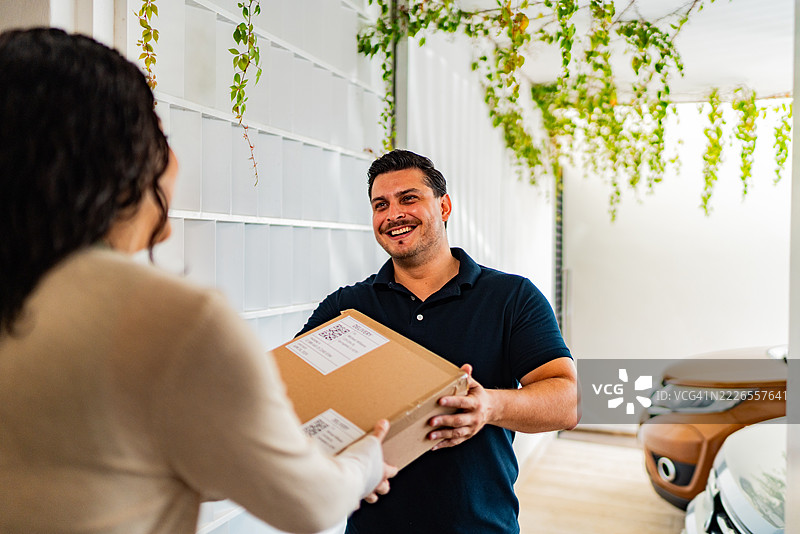 中年快递员将包裹送到客户家中图片素材