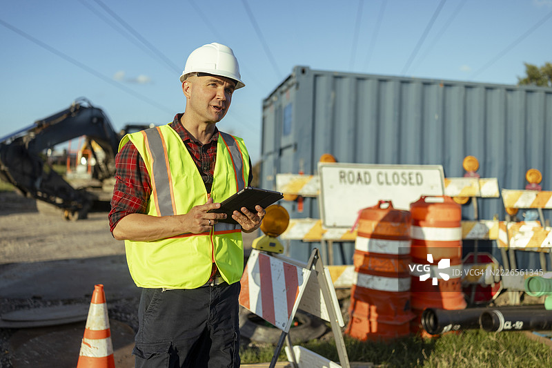 建筑工人在白天使用数字平板电脑监控道路施工图片素材
