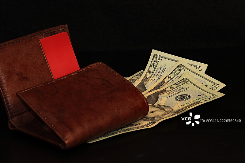 黑色背景上的美金二十美元钞票和棕色钱包图片素材