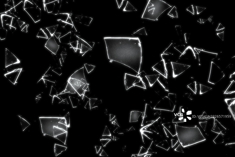 黑色背景上的破碎玻璃展示了碎玻璃的抽象纹理，细节丰富。该图像非常适合用作背景、纹理或抽象艺术项目。图片素材