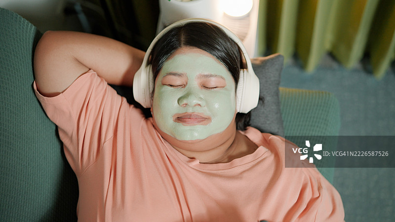 亚洲女性在沙发上使用面膜并小憩图片素材