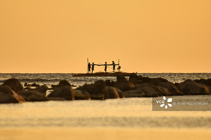 宁静的日落场景，温暖的金橙色天空映照在平静的水面上。图片素材
