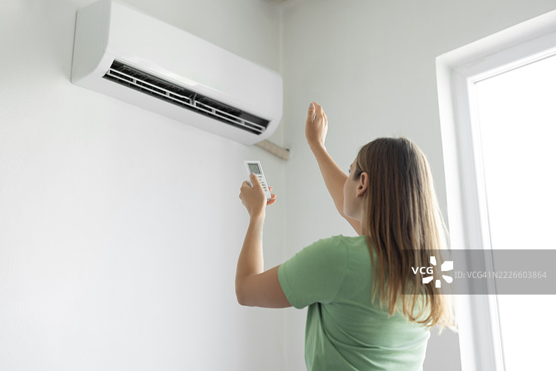 女人用遥控器打开空调图片素材