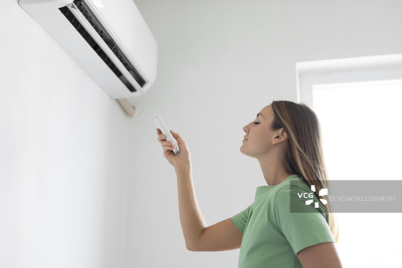 女人用遥控器打开空调图片素材