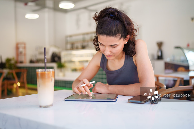女性顾客在咖啡馆使用数字平板和数字笔图片素材