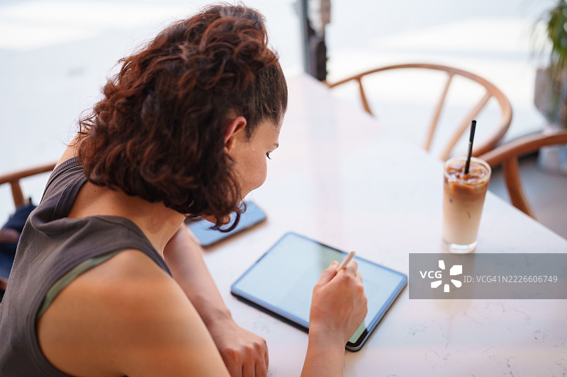 女性顾客在咖啡馆使用数字平板和数字笔图片素材