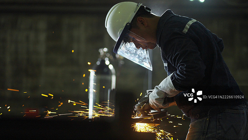 全副武装的熟练磨工在金属工厂熟练操作磨床。非常适合强调职业安全和先进制造技术。图片素材