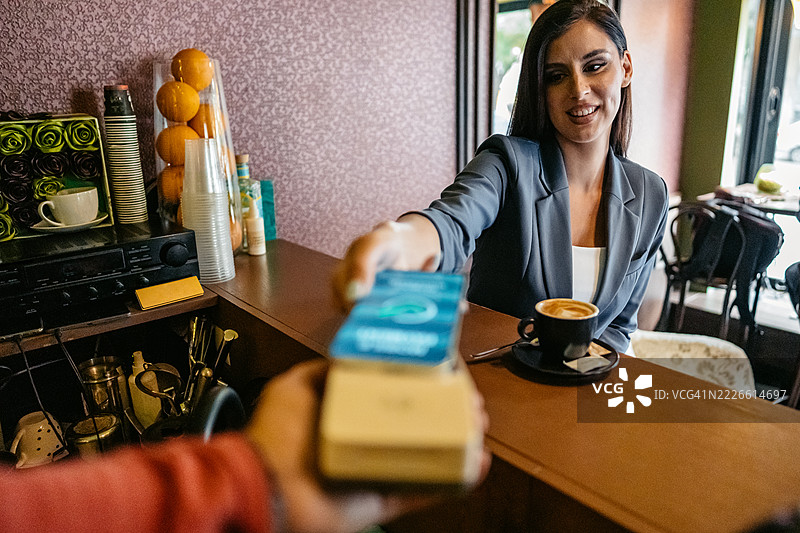 年轻女商人在咖啡店通过移动银行应用进行无接触支付图片素材