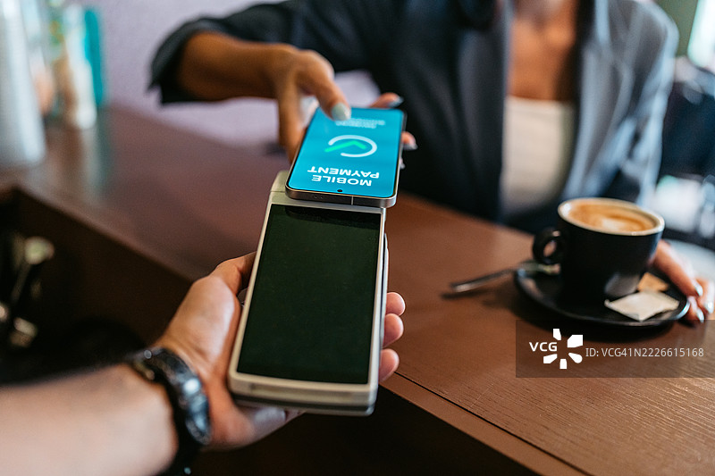 年轻女商人在咖啡店通过移动银行应用进行非接触式支付图片素材