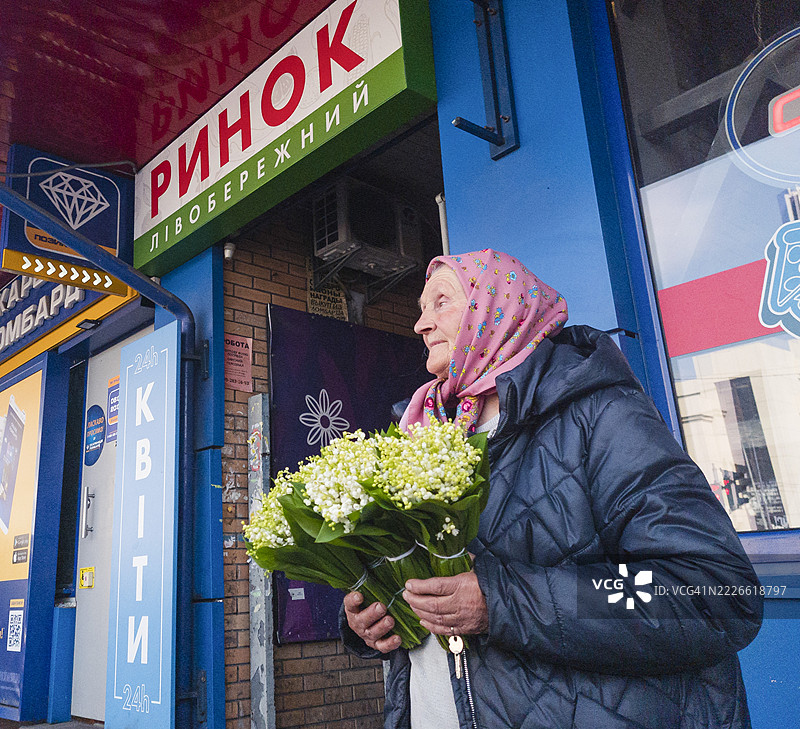在乌克兰基辅的一家花店前，一位老年女性正在出售铃兰花束。图片素材