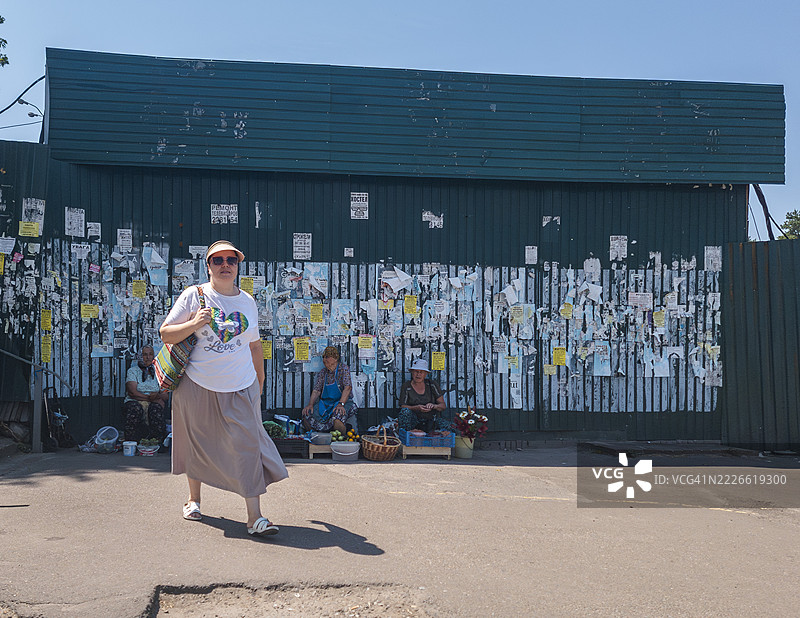 在乌克兰基辅的跳蚤市场上，一位女性走过，背景中有摊贩。图片素材