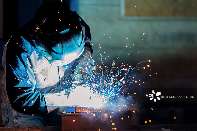 经验丰富的焊工在严格的安全规程下使用焊接火炬。闪烁的火花和浓厚的烟雾反映了钢材加工过程中所涉及的高温和电能。图片素材