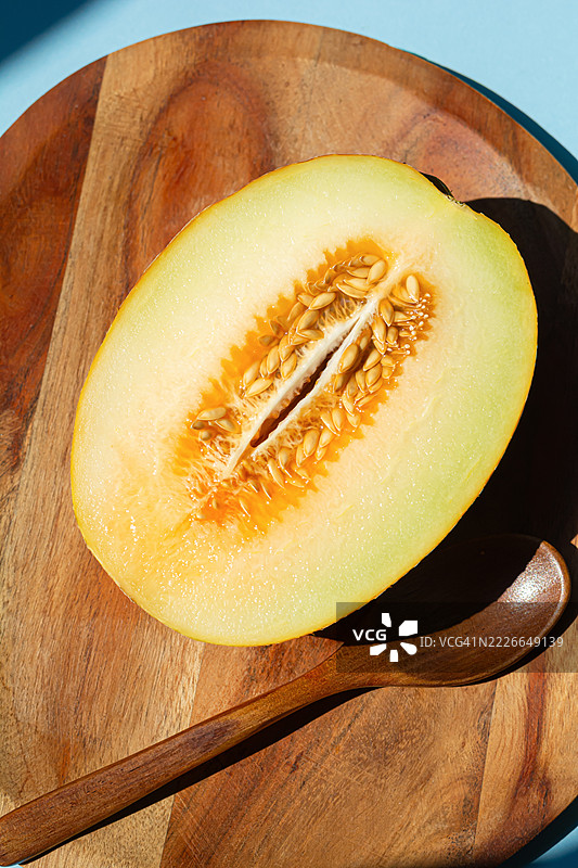 在蓝色背景下，成熟的半个哈密瓜，光线强烈，带有阴影效果。图片素材