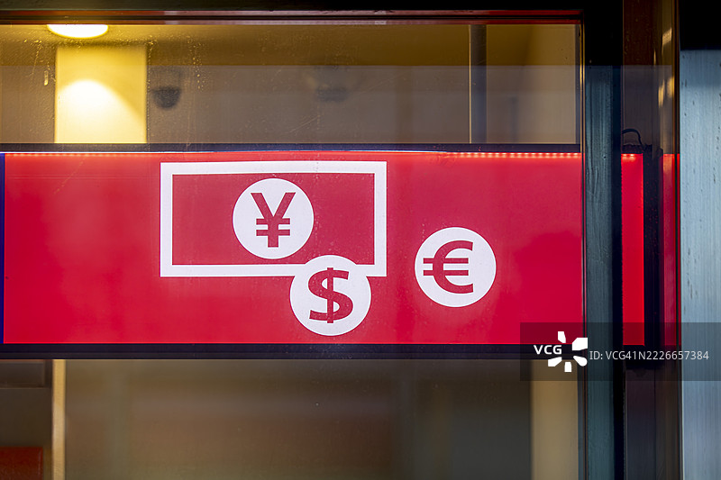 红色背景下的玻璃窗中展示的全球货币符号：日元、美元和欧元图片素材