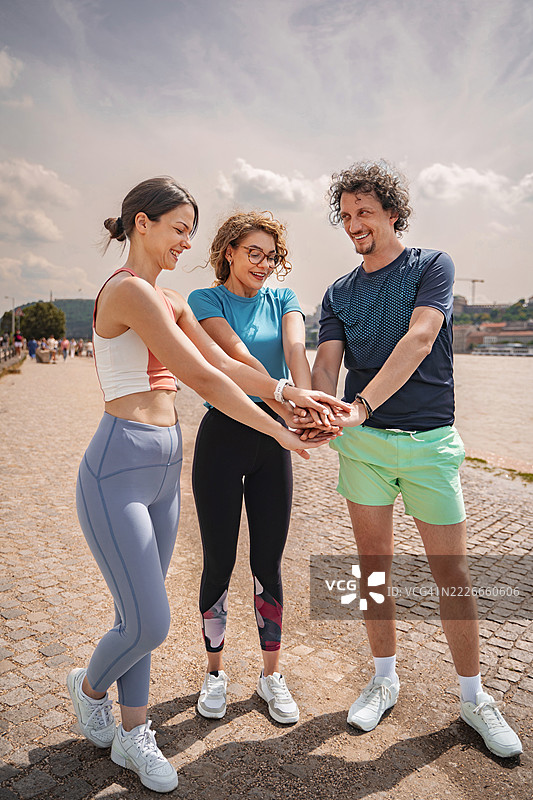 一群运动型朋友在户外锻炼前将手叠在一起图片素材