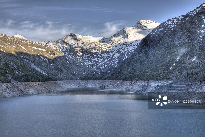 一个宁静的湖泊,嵌在被雪覆盖的山脉和岩石海岸之间,映衬着钢蓝色的天空,马特马克水库,山湖,山溪,瀑布,萨斯谷,萨斯阿尔马杰尔,萨斯费,瓦莱州,瑞士图片素材