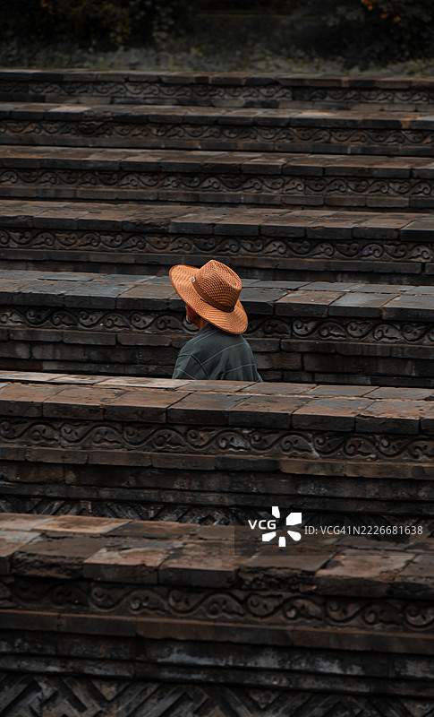 侧面视角的人戴着帽子走过木墙，北京，中国图片素材