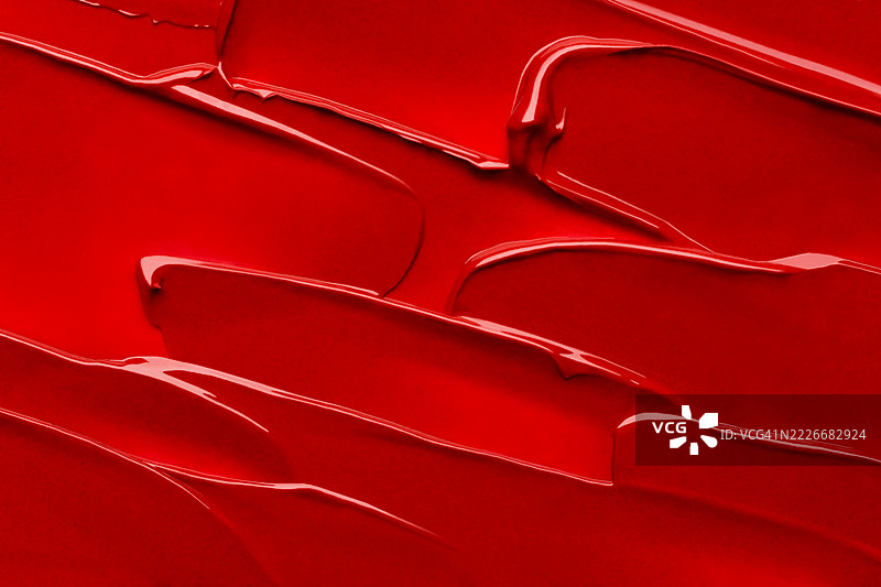 鲜艳的红色口红质地特写，展现光滑流畅的笔触和涂抹效果。大胆奢华的美容背景，完美适用于化妆品、化妆和护肤概念。抽象且细节丰富。图片素材