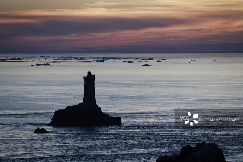 海边灯塔的剪影在日落时分映衬着天空，布列塔尼，法国图片素材
