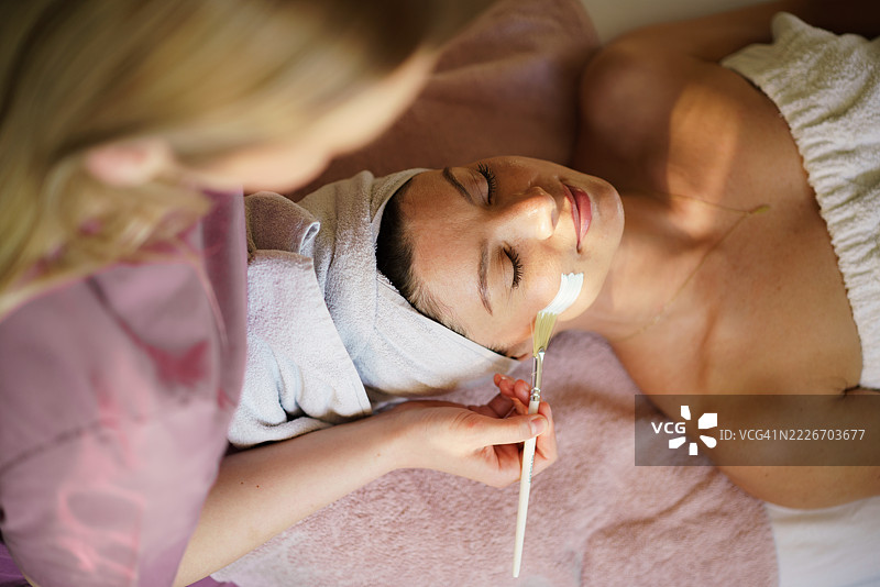 美容师正在用刷子为脸部涂抹面膜。图片素材