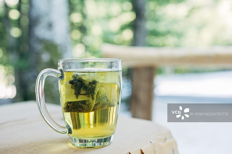 户外木桌上玻璃杯中的草本茶正在冲泡图片素材