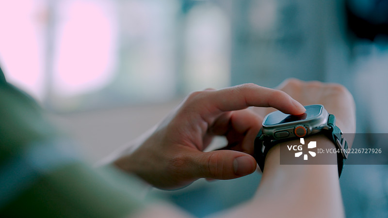 年轻的亚洲男子在健身房准备日常锻炼，正在设置智能手表。图片素材