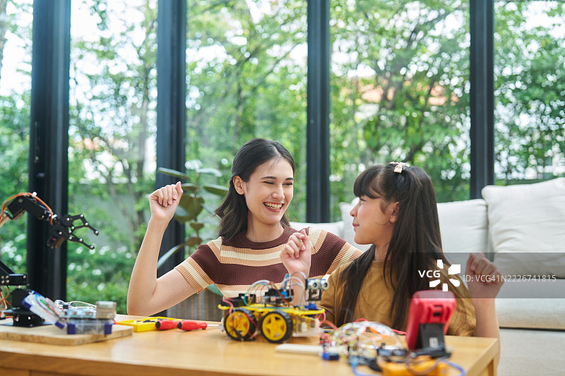 亚洲教师和学生在现代教室庆祝机器人成功图片素材