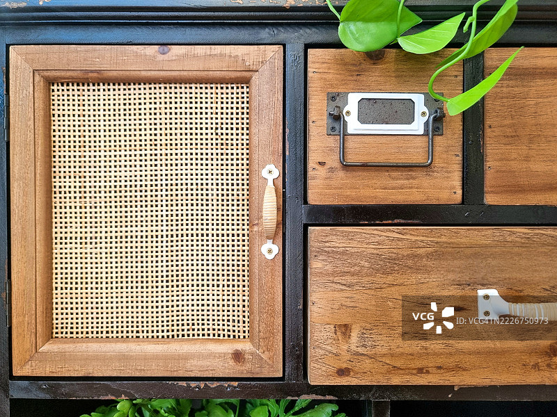 手工制作的复合风格储物柜，结合了乡村木材、藤编和植物细节，营造出宁静的家居优雅感，展现了复古风格的魅力。图片素材