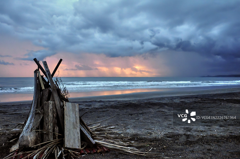 一堆木材和树叶，堆放在沙滩上，准备生篝火。图片素材