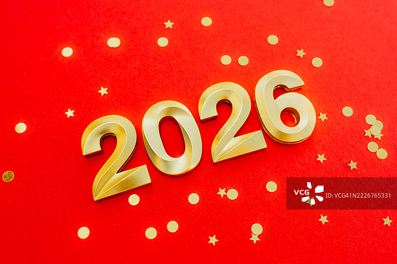 红色背景上方视角的金色数字2026，周围有金色的五彩纸屑。节日新年贺卡。图片素材