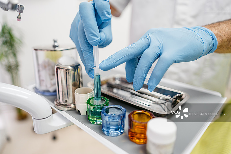 年轻男牙医在牙科办公室准备注射器中的药物图片素材