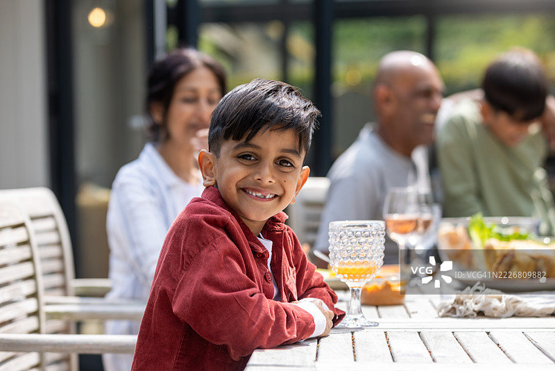 户外家庭聚会上微笑的年轻男孩图片素材