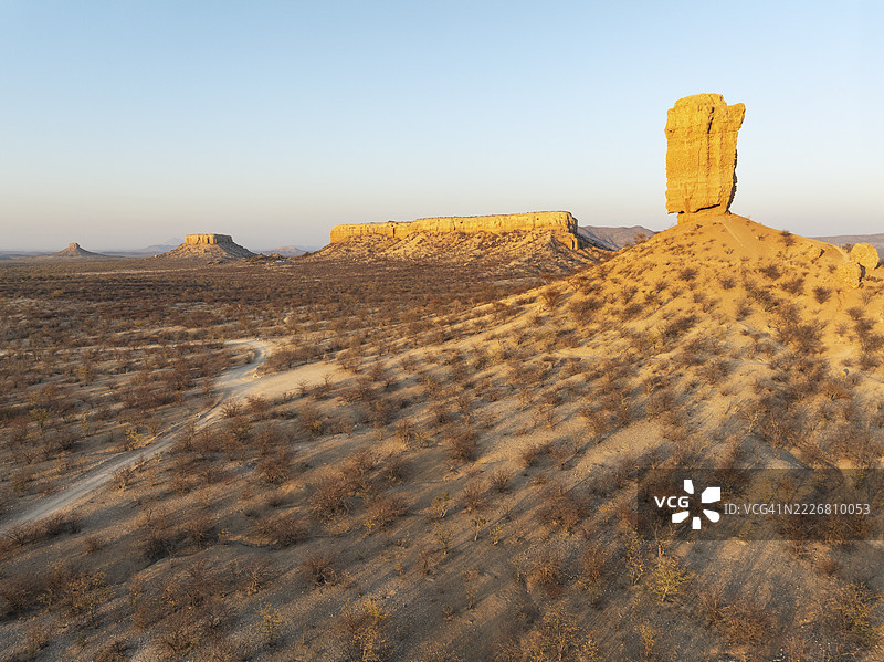 维根克利普（岩石手指）和乌加布谷地的梯田被荆棘灌木和莫帕尼（莫帕尼树）草原环绕。鸟瞰图。无人机拍摄。纳米比亚达马拉兰。图片素材