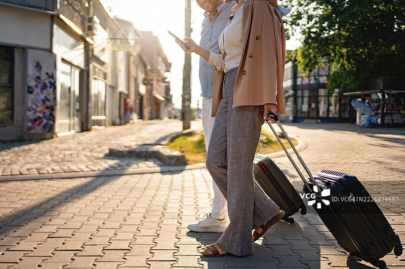 一对情侣在白天沿着鹅卵石街道一起旅行，拖着行李图片素材