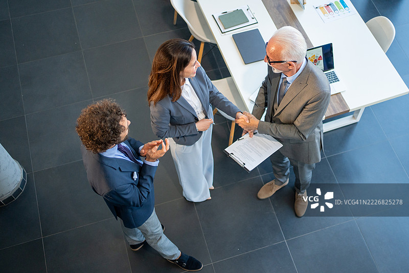 商务人士在现代办公室签署合同后握手图片素材