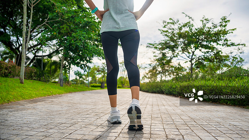 年轻女性跑者的脚在路上奔跑，鞋子特写。女性的腿准备在路上跑步。女性在阳光明媚的日子里走在跑道上。女性在户外公园锻炼。户外健身。健康生活方式和身体活动的概念。图片素材