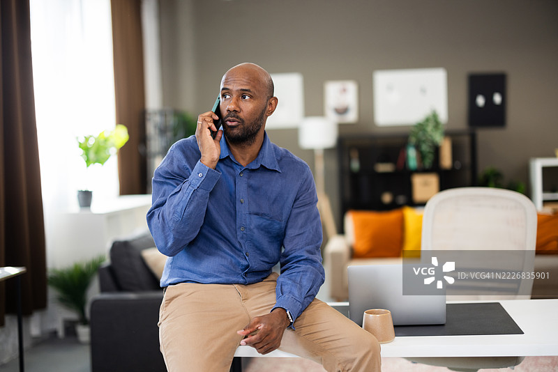 商人在家办公桌前坐着打电话图片素材