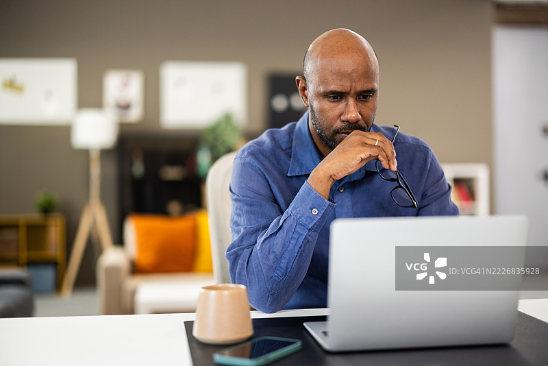 专注的黑人商人在家办公室使用笔记本电脑工作图片素材