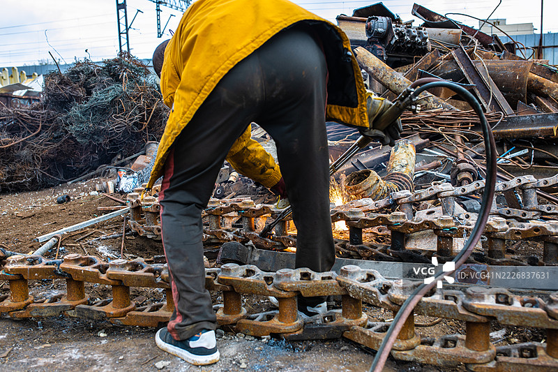 工人在废料场穿着防护装备焊接重金属链条图片素材